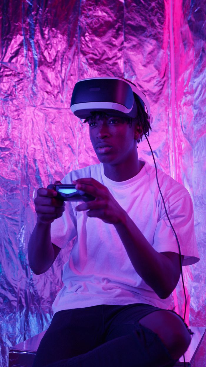 services-10 Young man wearing VR headset and gaming with intense neon backdrop, fully immersed in virtual reality.